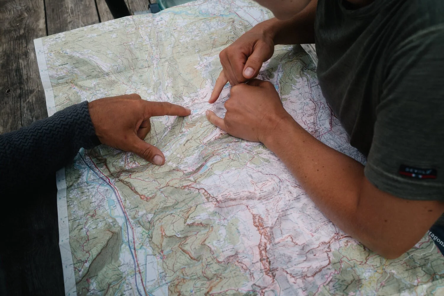 Deux personnes tracent leur itinéraire sur une carte topographique de montagne.