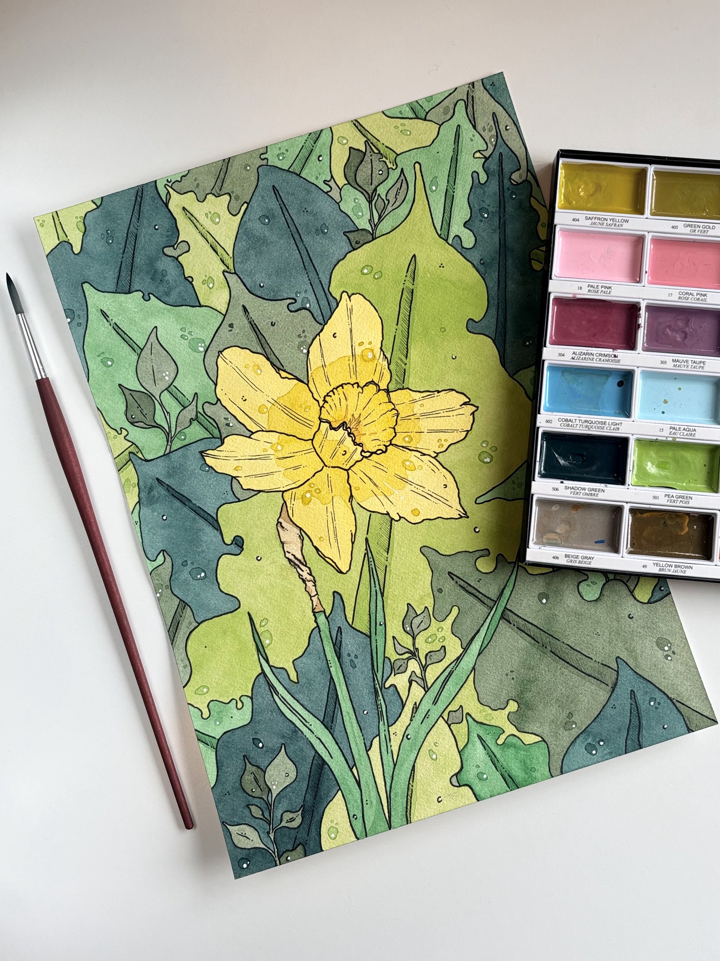 Colorful watercolor illustration of green leaves and a yellow daffodil with a paintbrush and watercolor palette nearby.