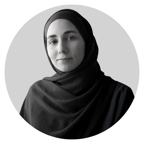 Black and white portrait of a woman wearing a hijab, looking at the camera with a slight smile.