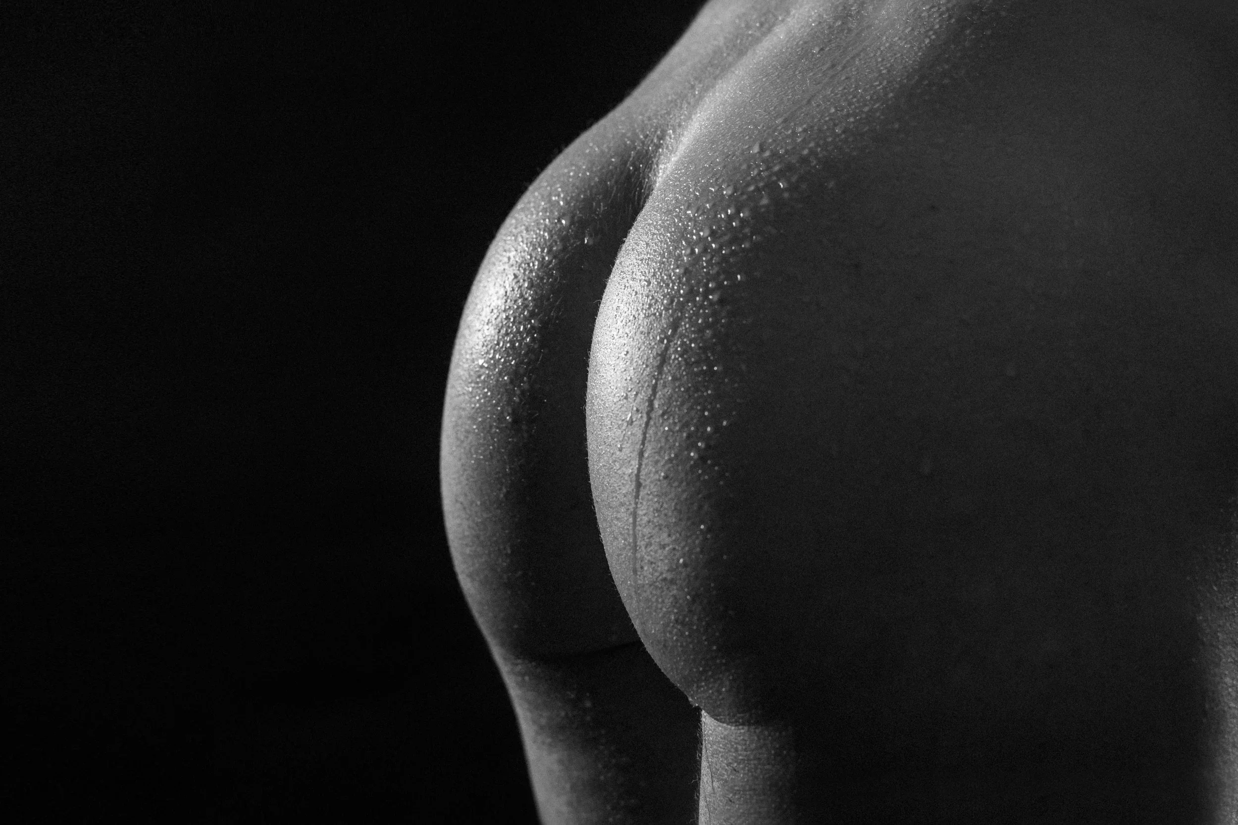 A close-up, black and white photograph of a curved object with water droplets on its surface.