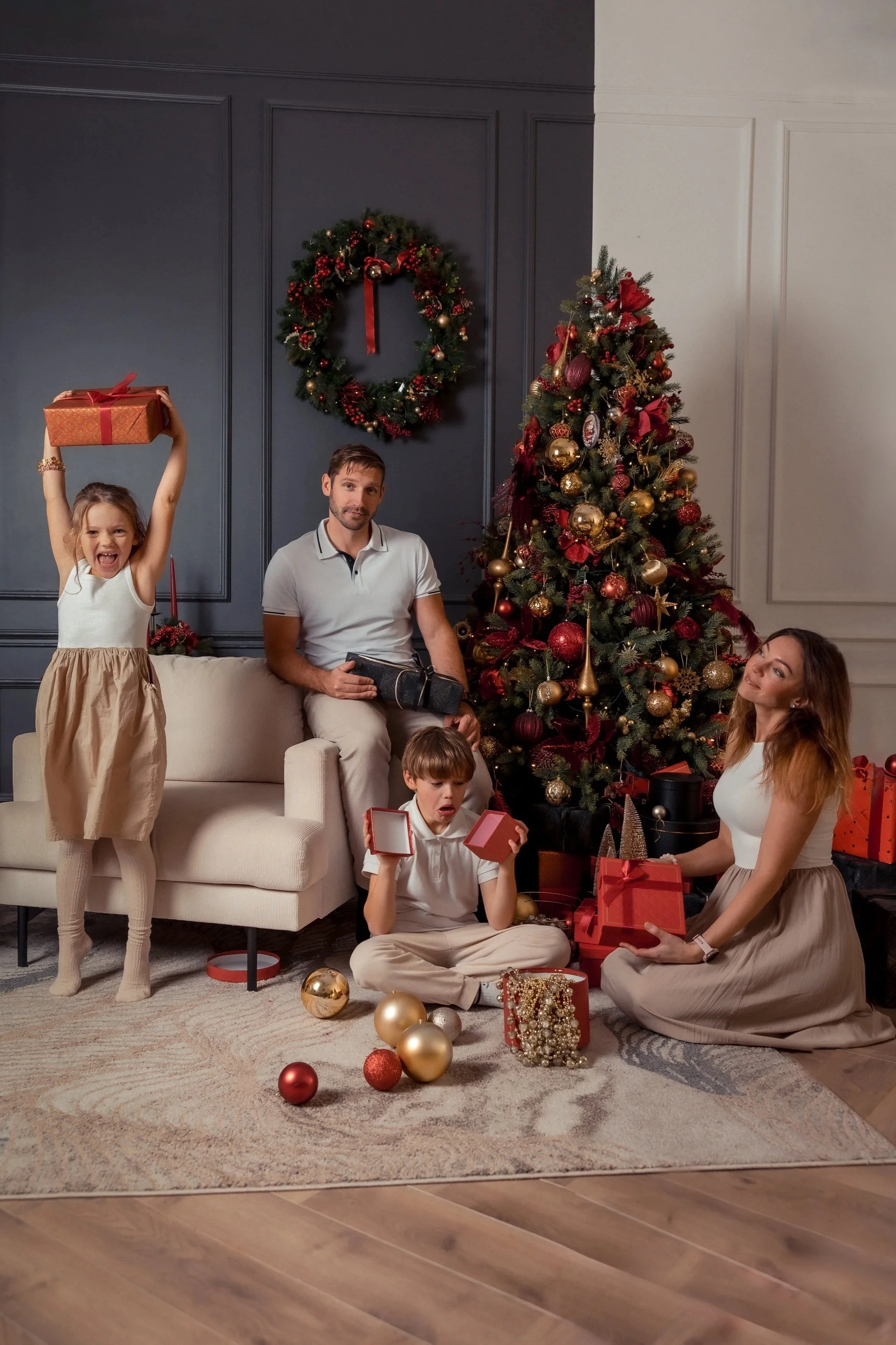 A family celebrating Christmas with a decorated tree and gift exchange in a cozy living room.