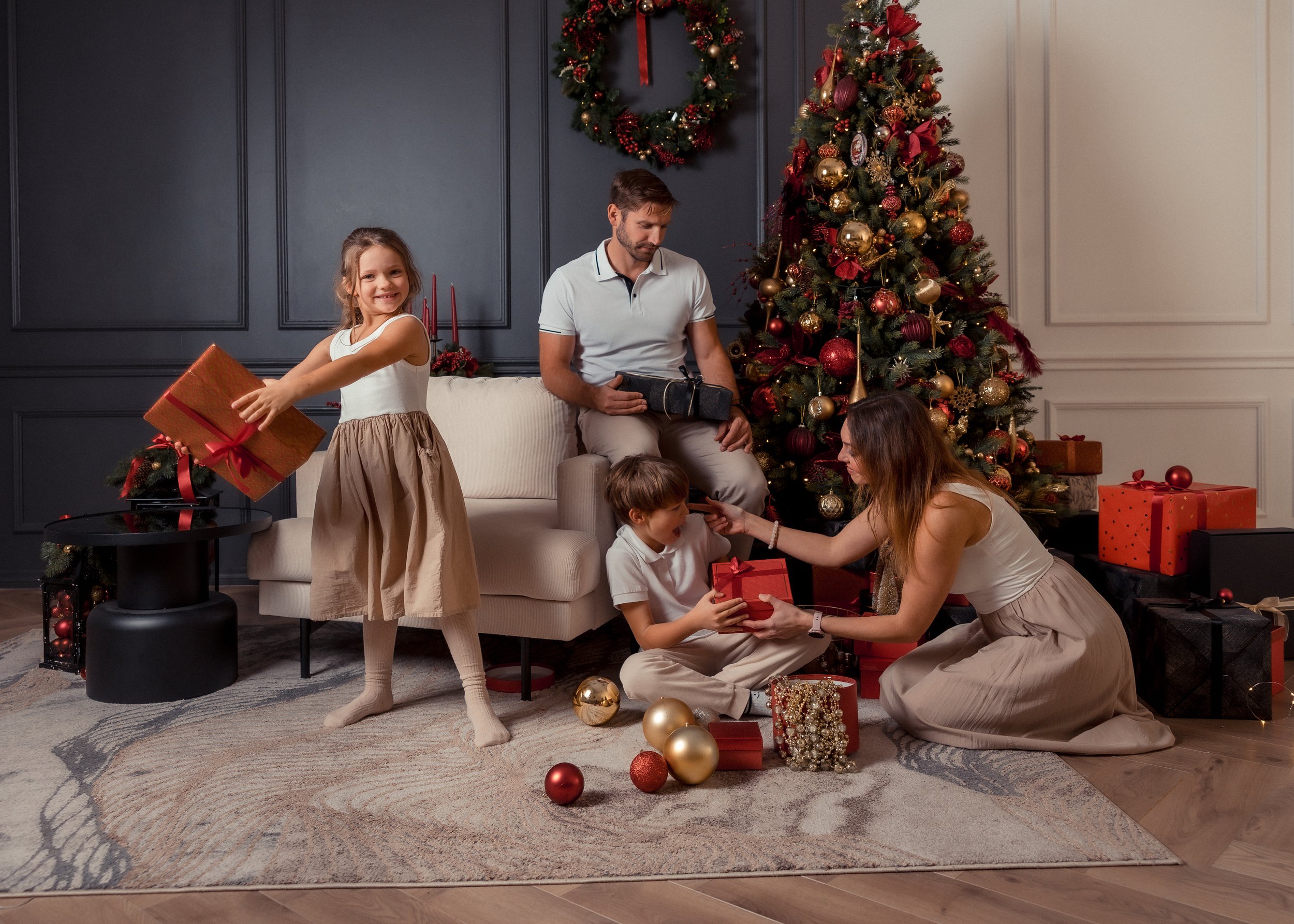 Family celebrating Christmas, exchanging presents around a decorated Christmas tree in a cozy living room.
