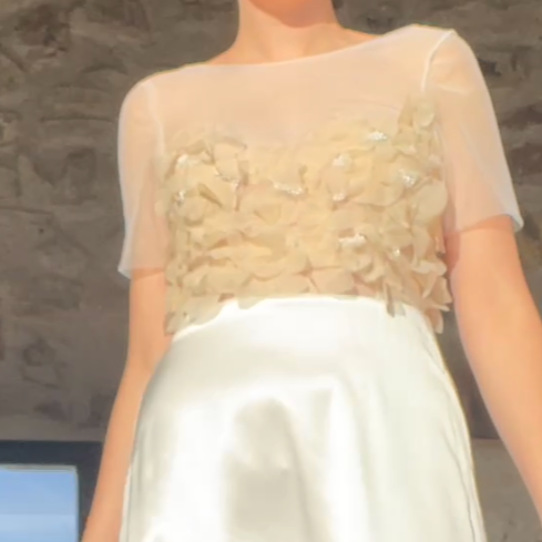 Vestito da donna bianco con decorazioni floreali sulla parte superiore, indossato da una persona.