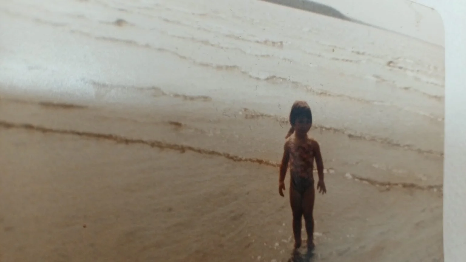 Deirdre Burton as a child standing on the beach