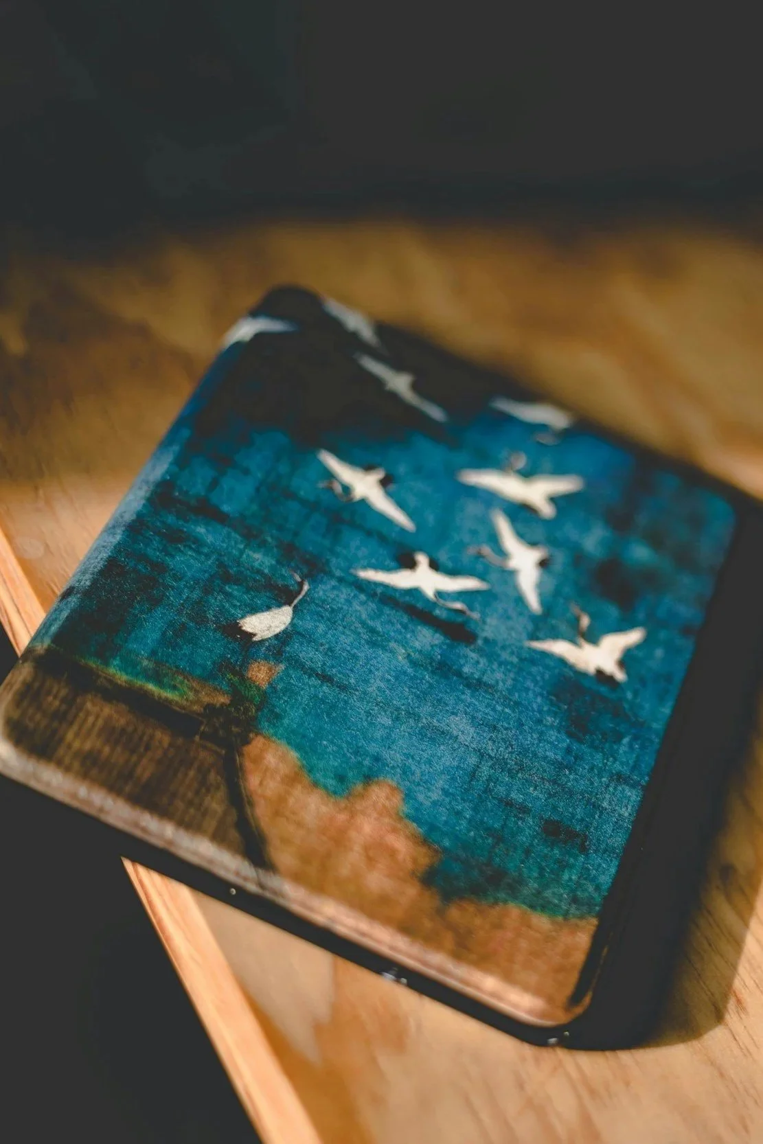 Carnet fermé bleu et marron orné d'oiseaux blancs stylisés en envol, symbole d'écriture et de libération