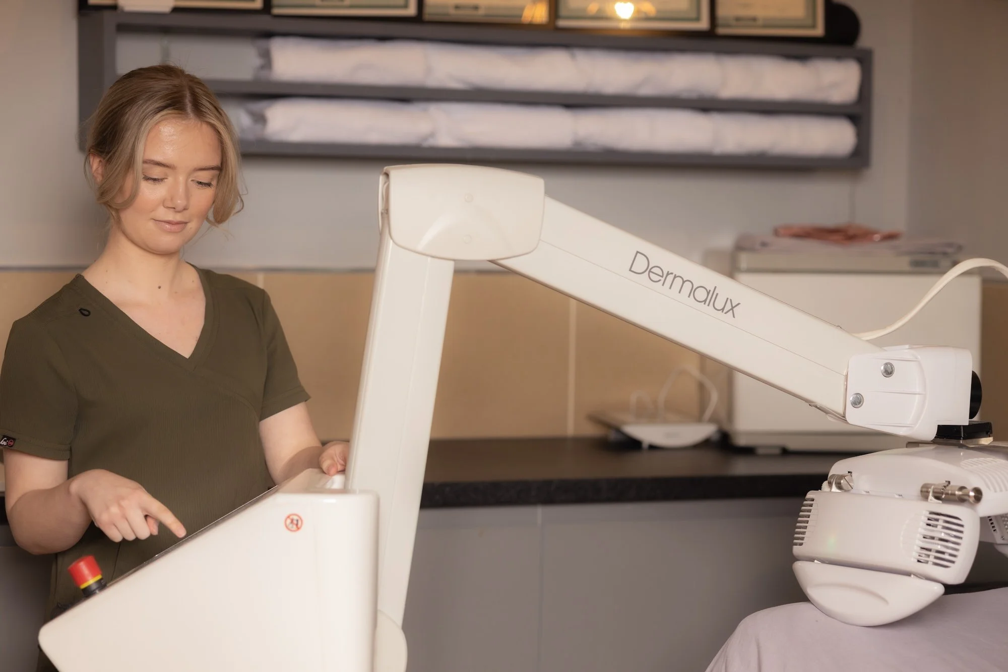Aesthetician using Dermalux LED therapy machine in a spa setting.