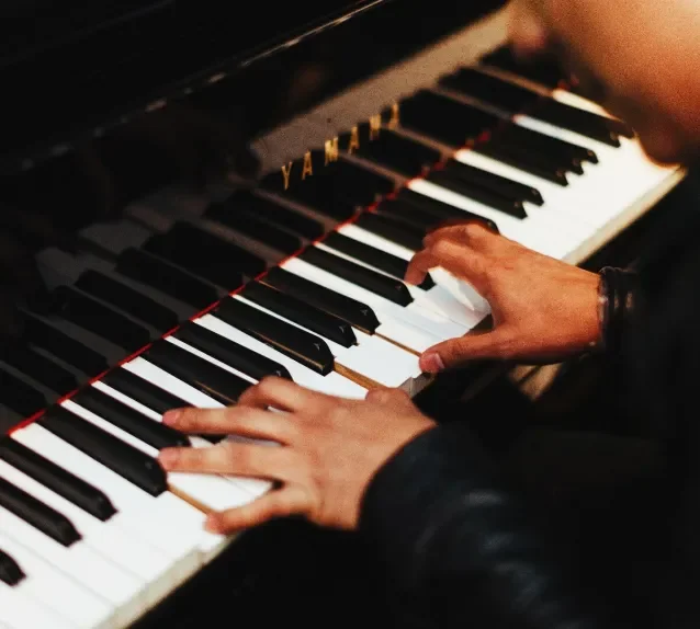 Person playing a black Yamaha piano, with hands on the white and black keys.