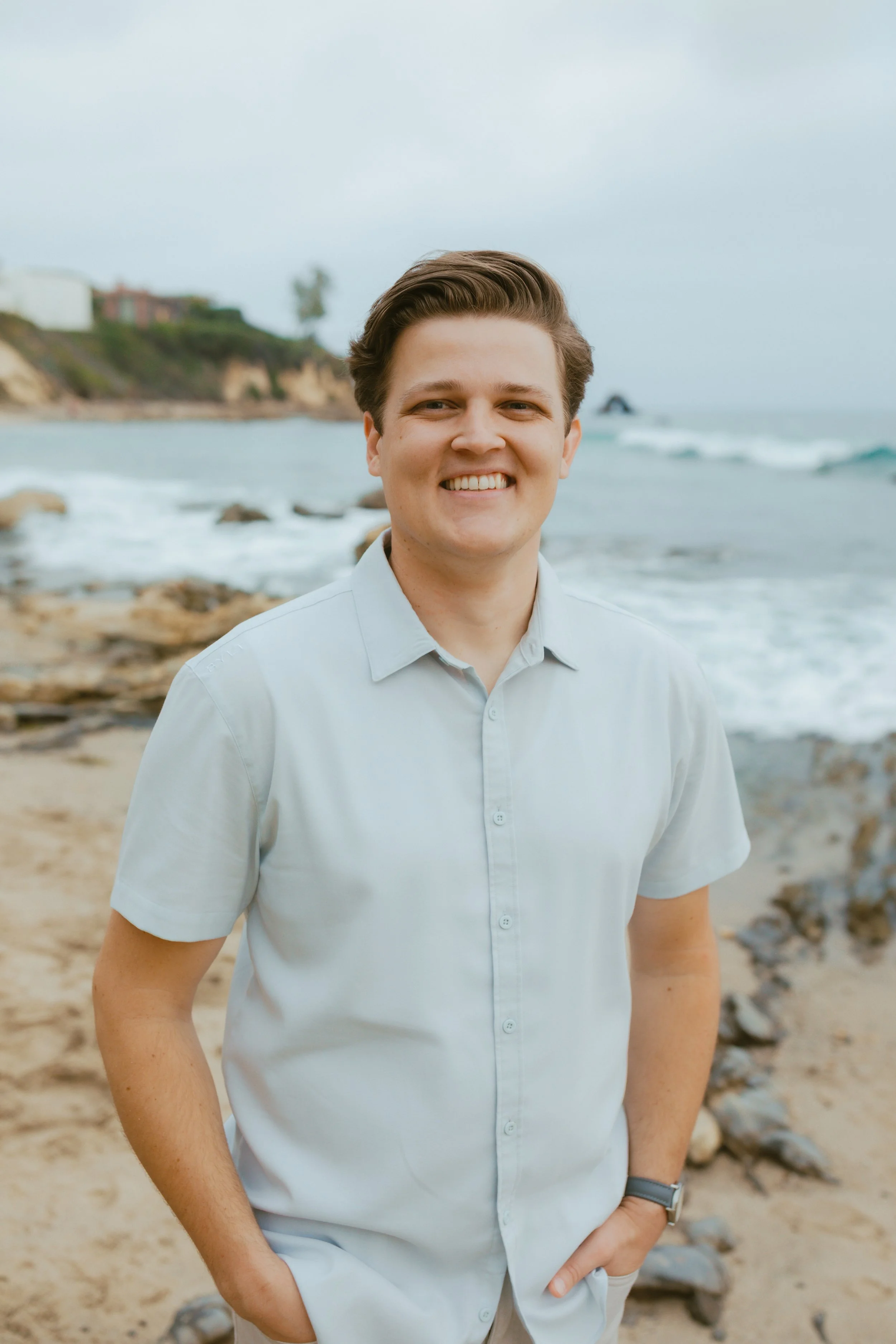 Dr. Rennie smiling on a beach, wearing a blue polo.
