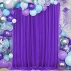 Purple curtain backdrop surrounded by purple balloons and decorations