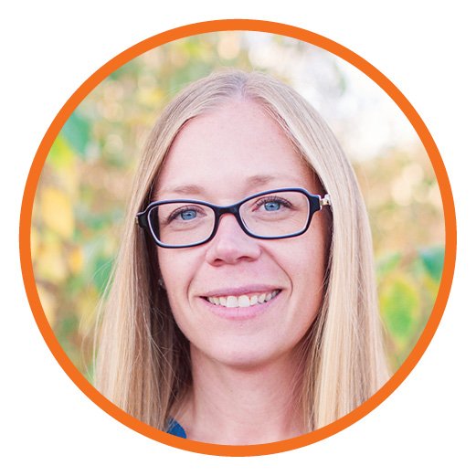 A woman with long blonde hair and glasses smiling outdoors, framed by an orange circular border.