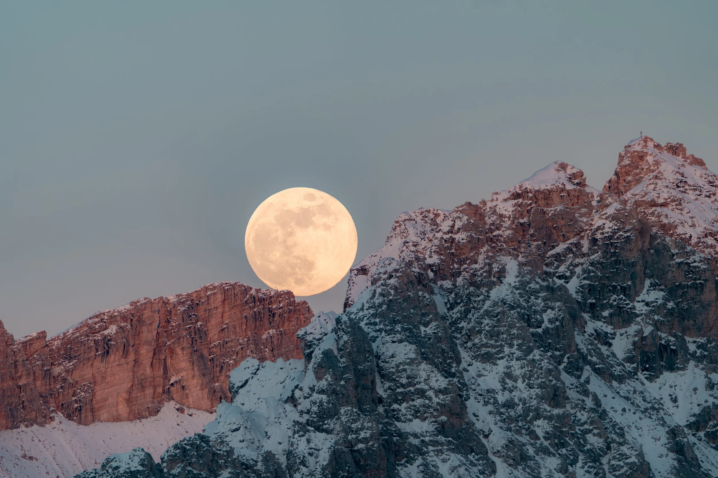 Vollmond über schneebedeckten Bergen bei Sonnenuntergang