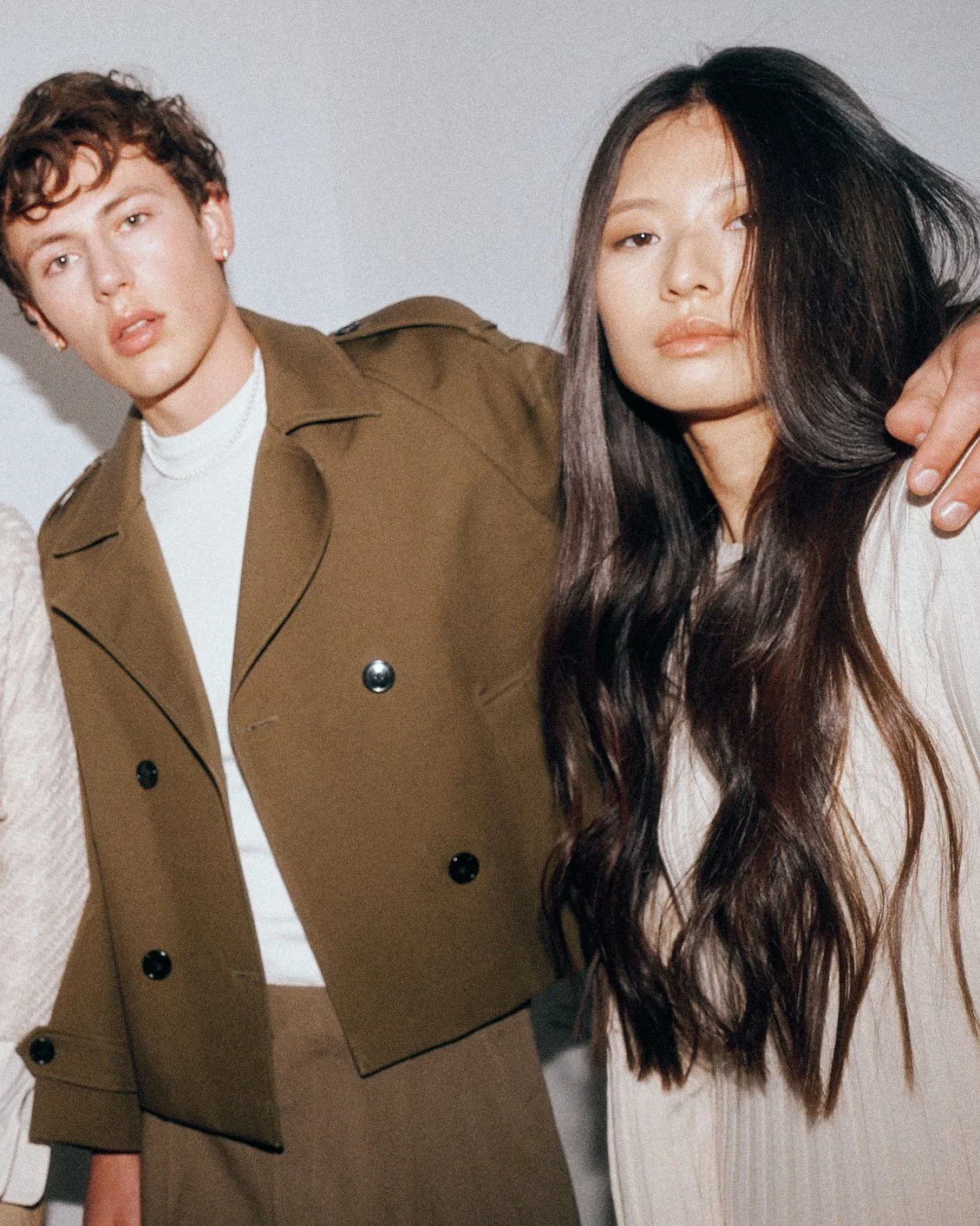 Man in a brown jacket standing beside a woman in a cream blouse with his arm around her.