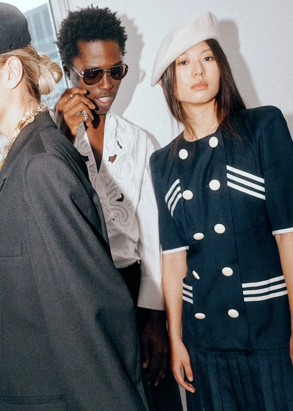 Man in sunglasses and a dark jacket beside a woman in a navy dress and pale beret.