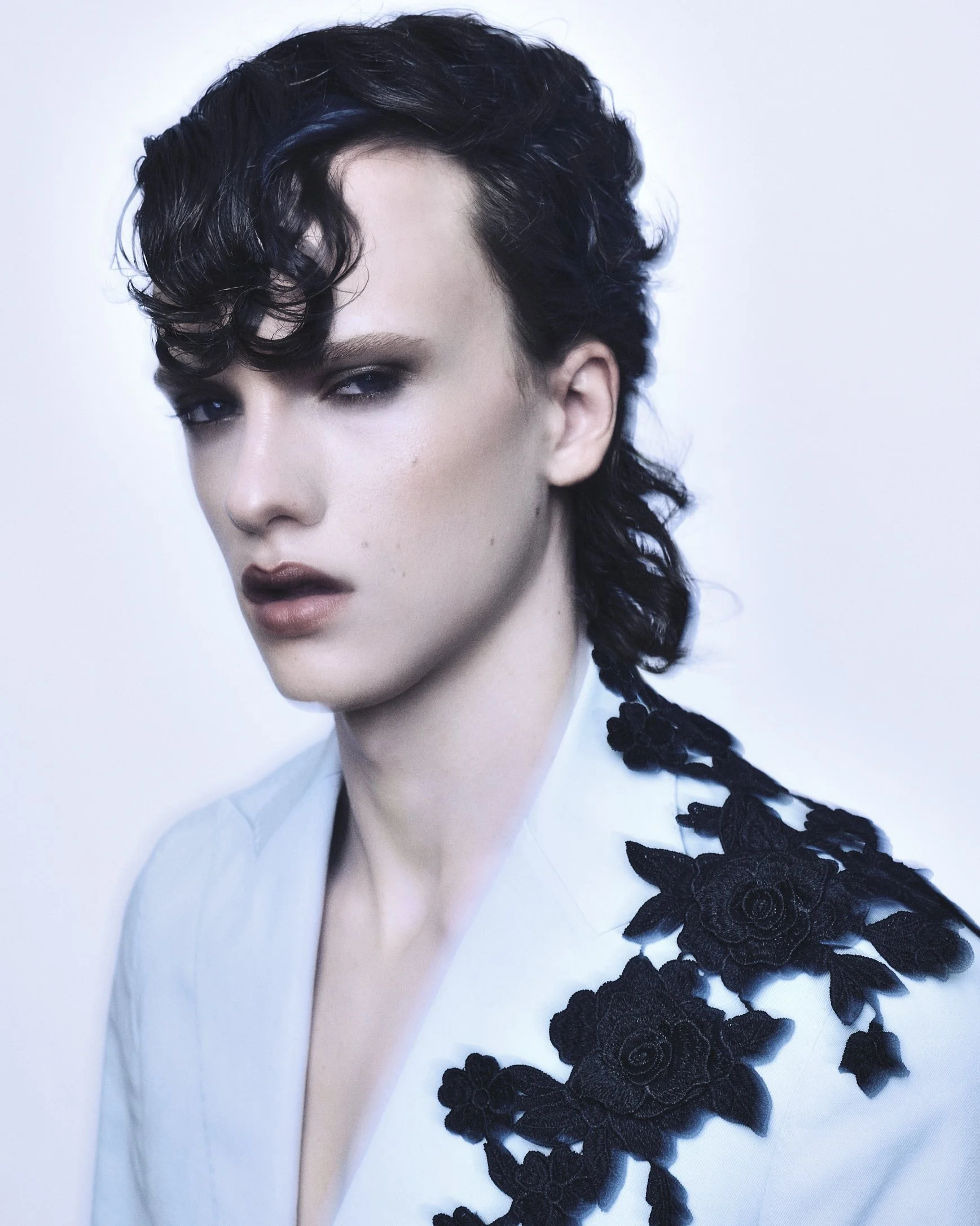 Beauty portrait of a model with dark curled hair, smoky makeup and a black-and-white lace outfit.