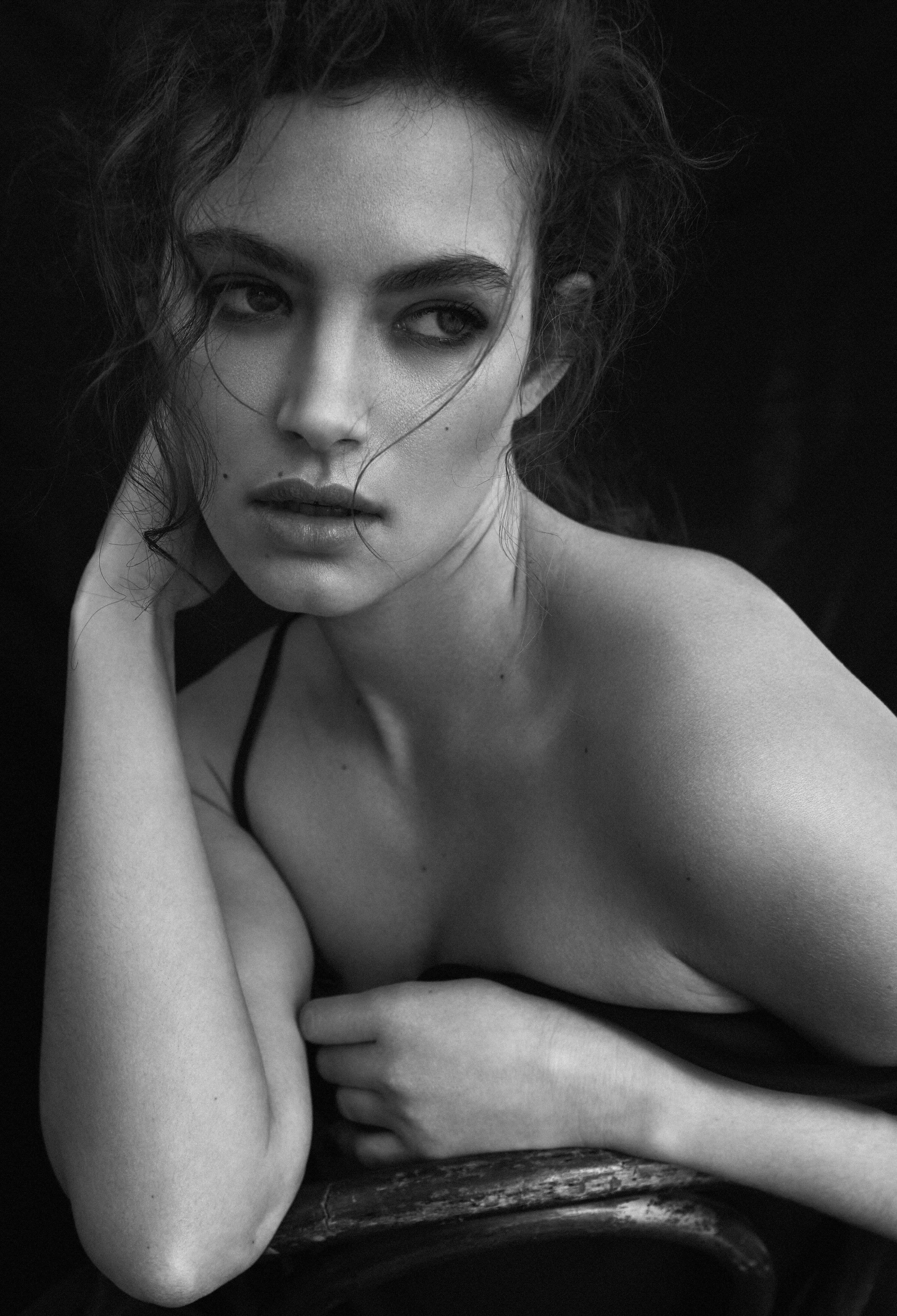 Black-and-white close-up of a woman with loose hair resting her face against her hand.