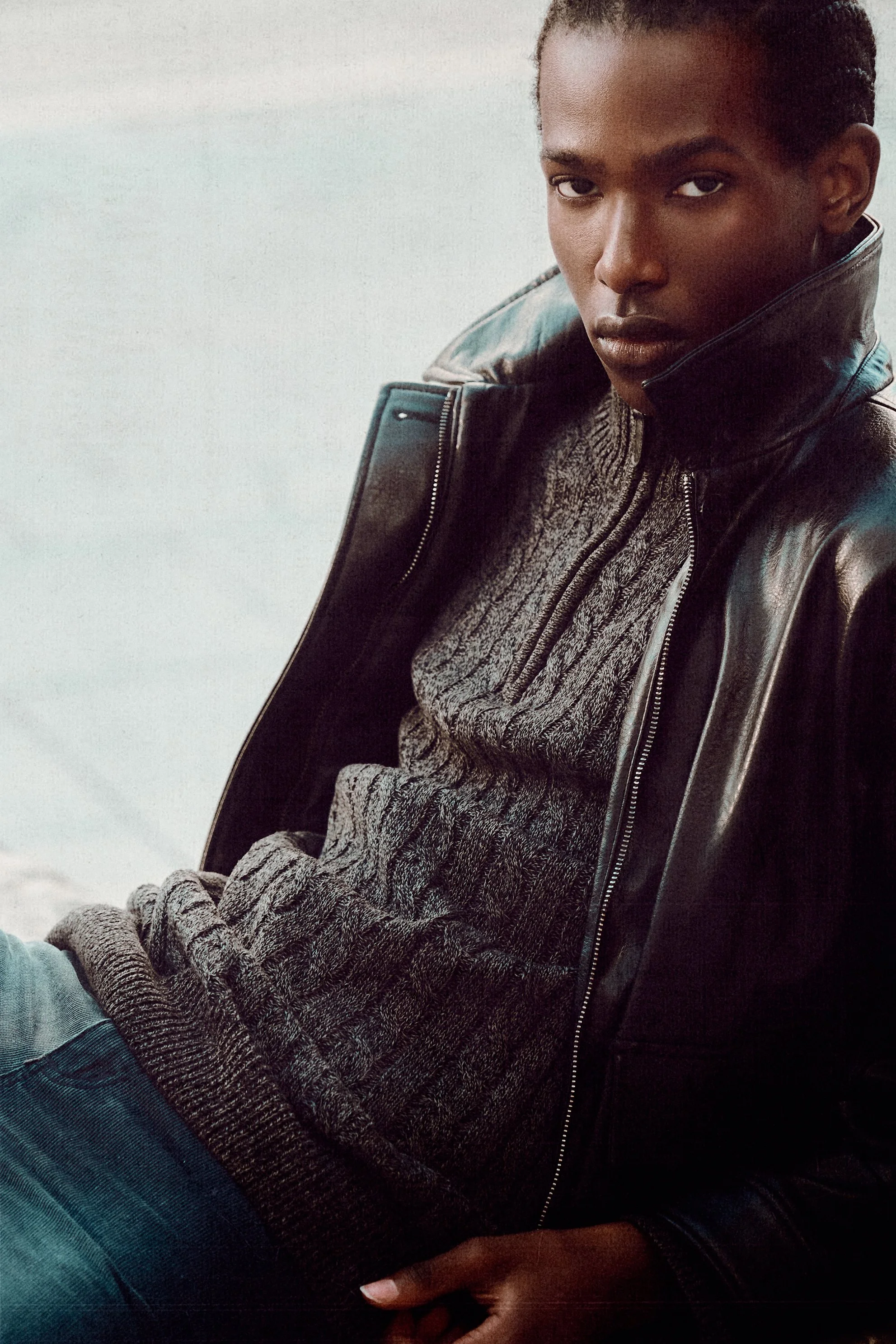Close portrait of a man in a cable-knit sweater and leather jacket with the collar raised.