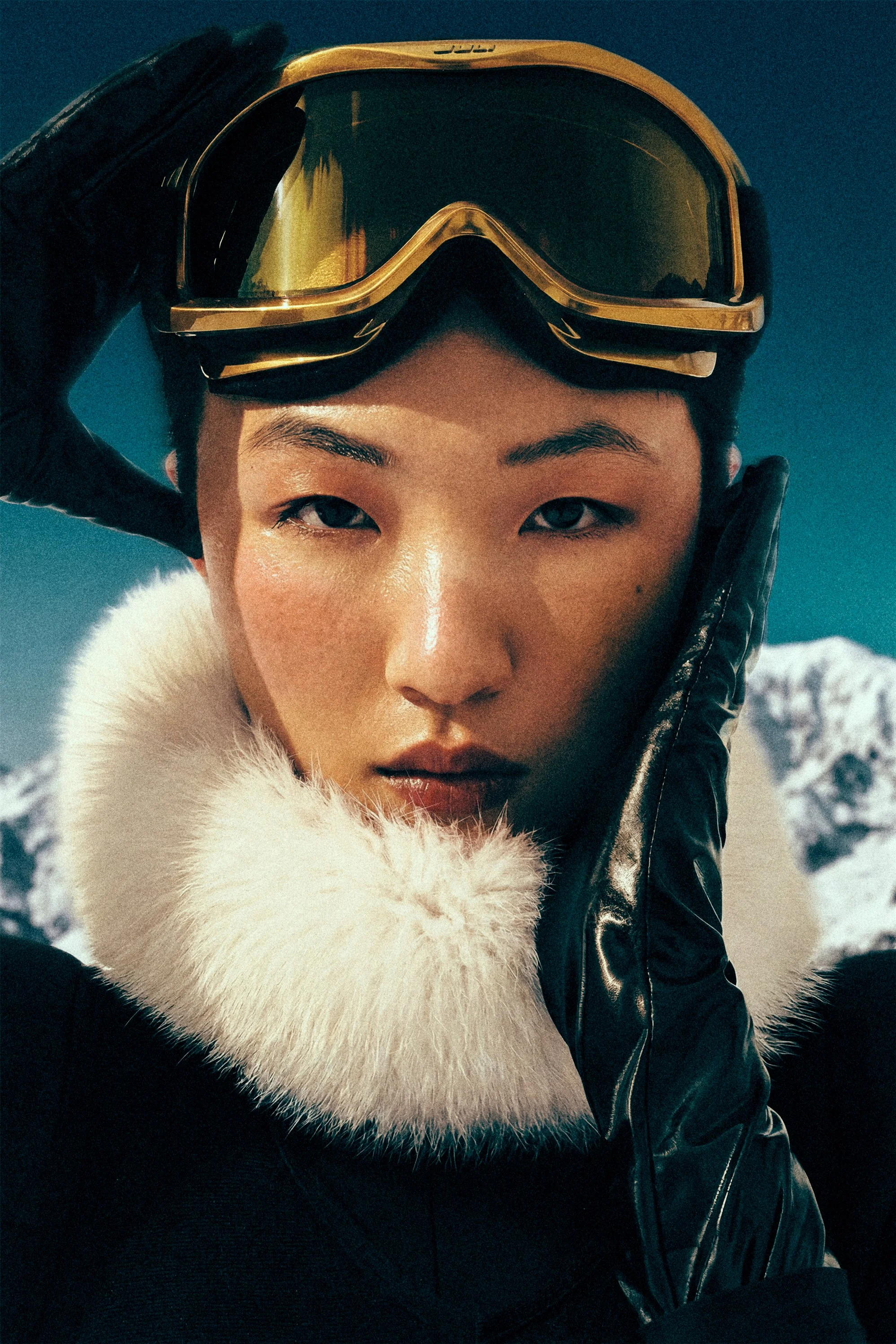 Close portrait of a woman wearing ski goggles above her forehead and a white fur collar.
