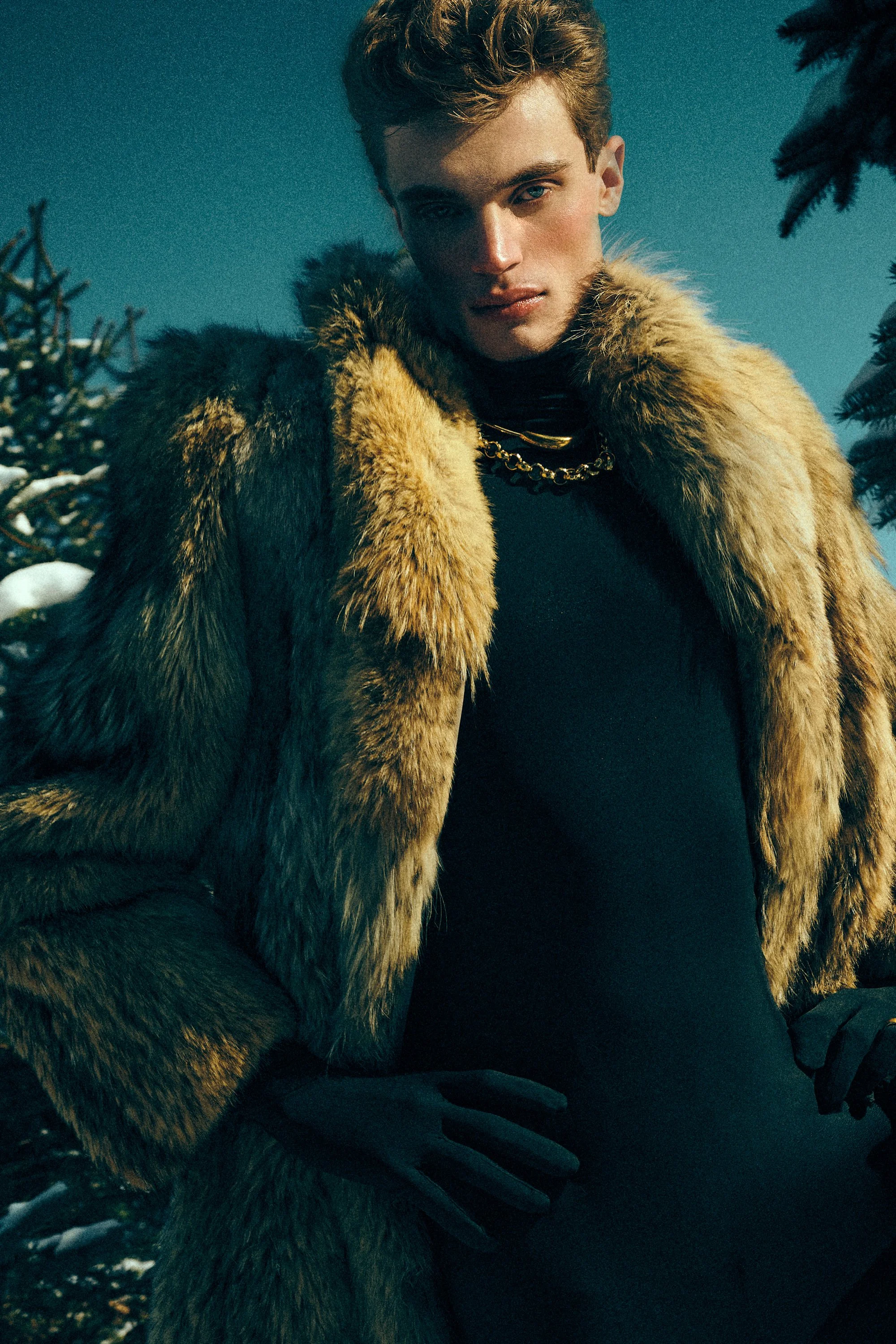 Man wearing a brown fur-textured coat over a black turtleneck outdoors in winter.