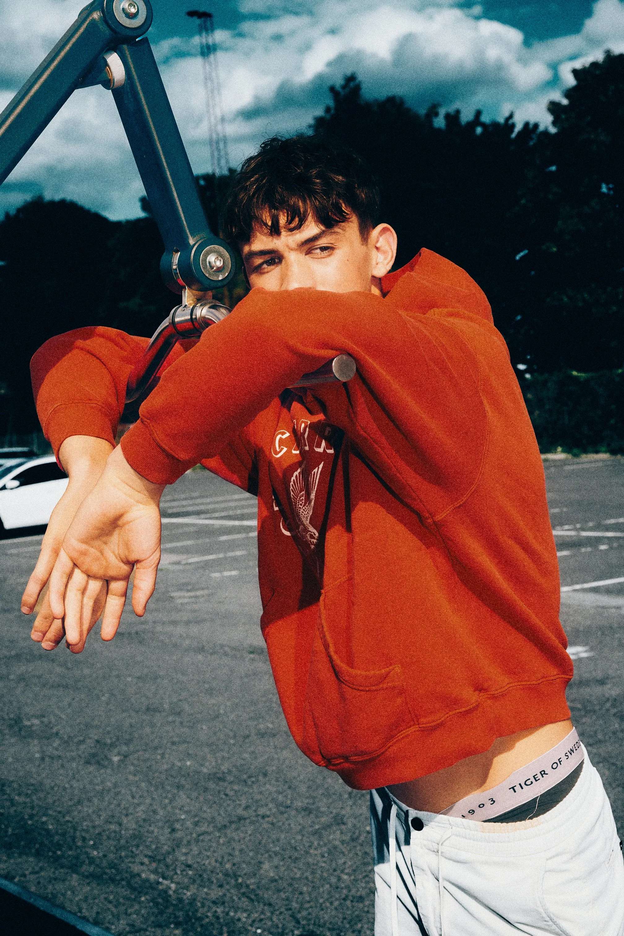 Close portrait of a man with the sleeve of a red sweatshirt across his face.