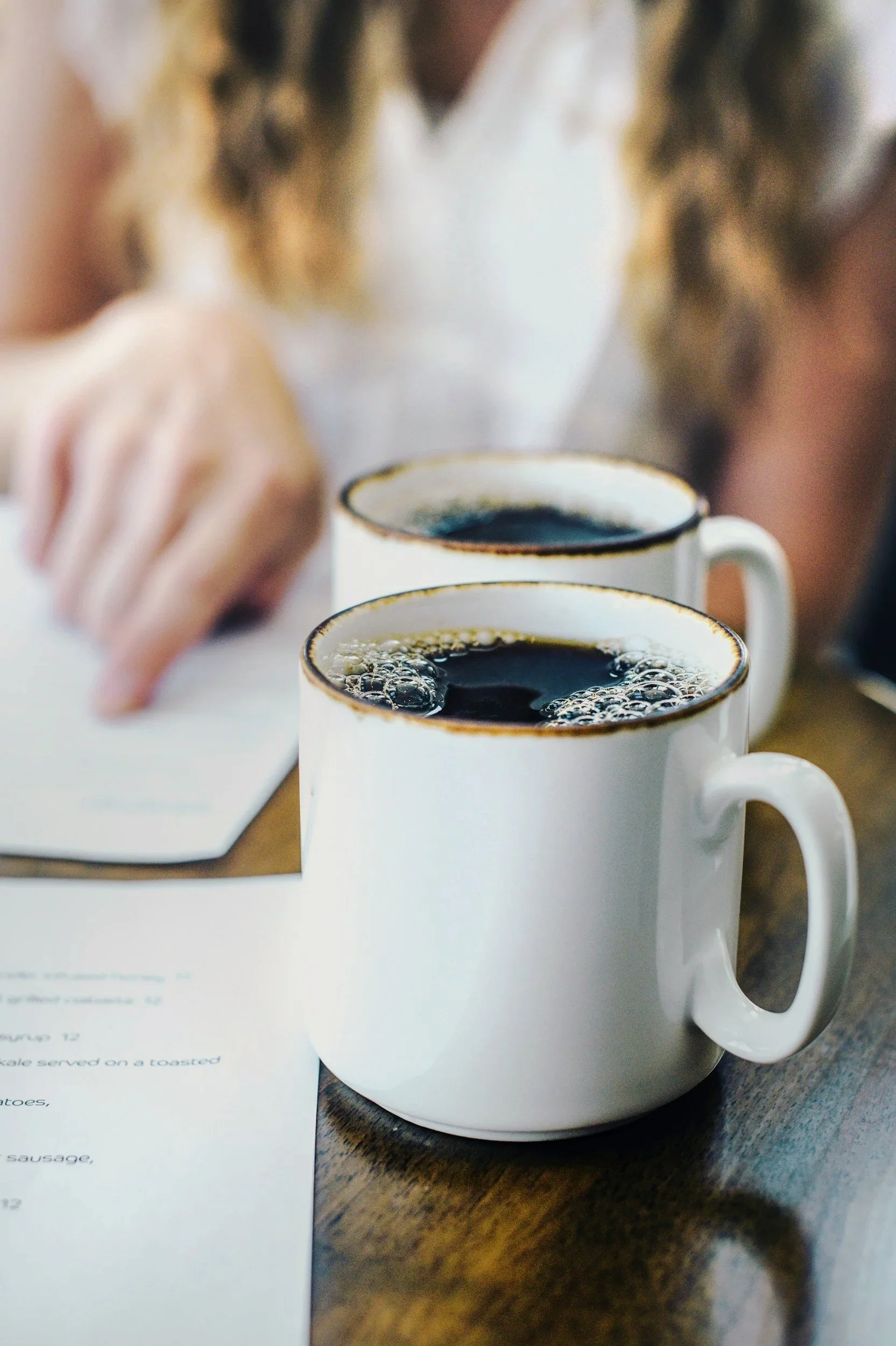 Two cups of coffee on a table in a warm, relaxed home setting.