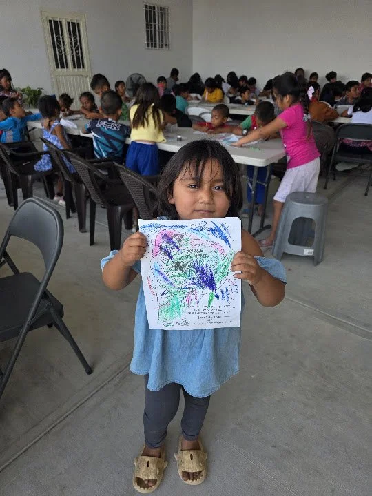 A child holds up her colorful artwork during an activity at the community center.