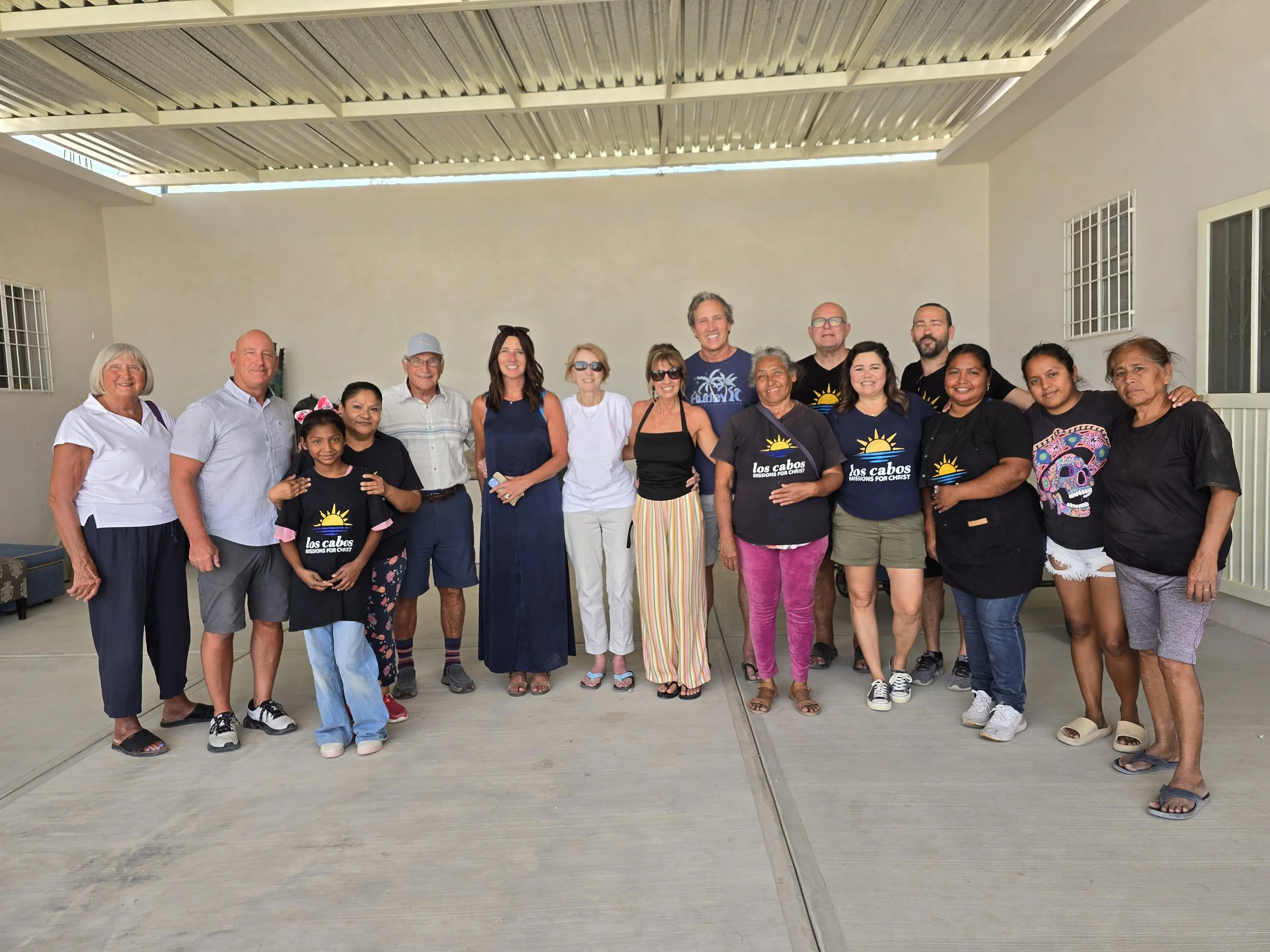 Group of diverse people standing on a covered outdoor patio, smiling and posing for a photo.