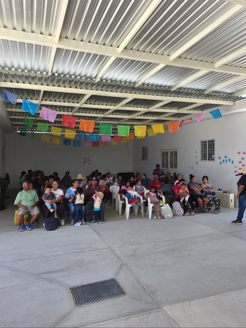 Families seated together under the community center roof during an outreach event.