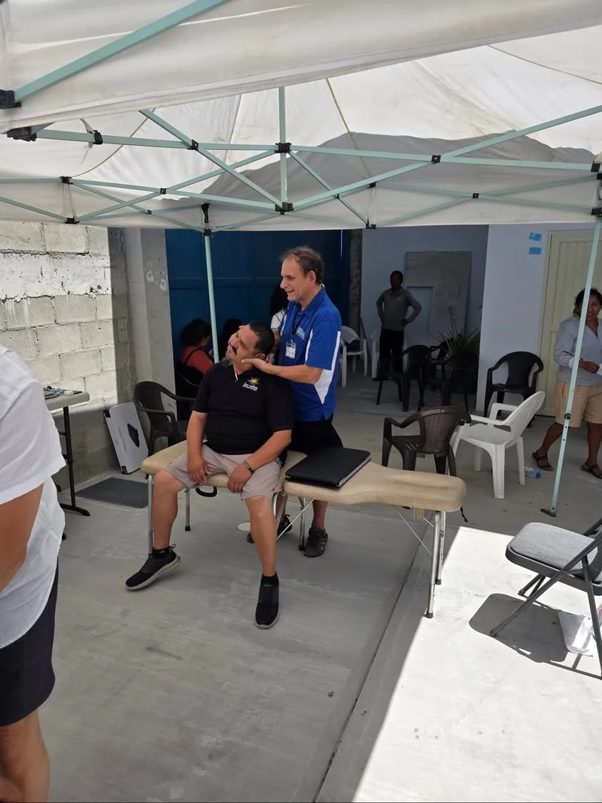 Volunteers talking with a visitor beneath a canopy at a community outreach event.