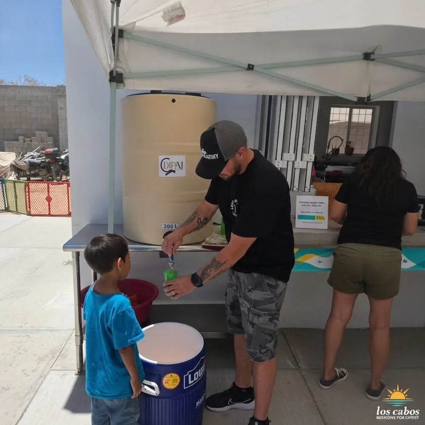 Un voluntario sirve agua a un niño en el centro comunitario.