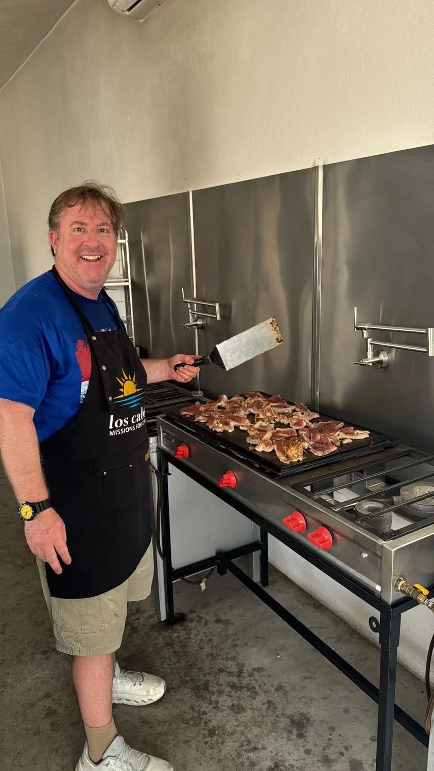 Volunteer preparing food on a griddle at the Los Cabos Missions for Christ community kitchen.