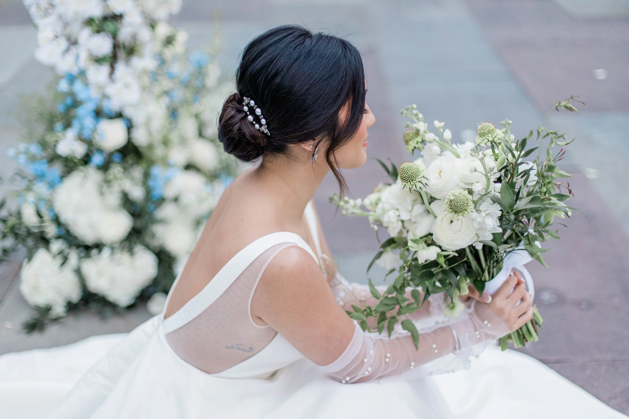 Bride sitting with Boquet of White florals and Greenery