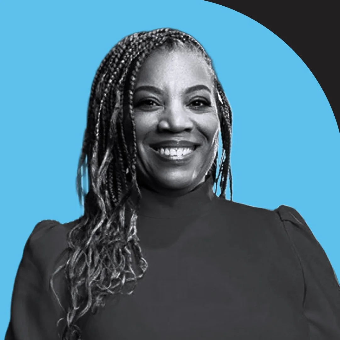 Black and white portrait of a woman smiling, wearing a dark top, with braided hair, set against a blue circular background.