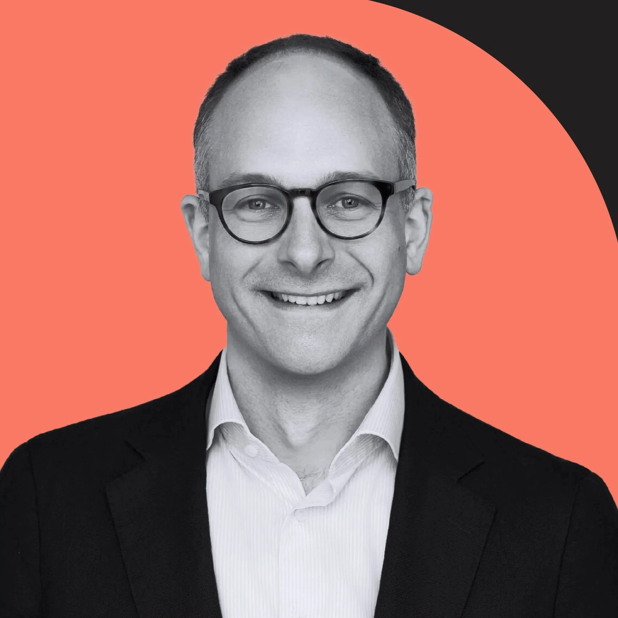 Black-and-white portrait of a man wearing glasses, smiling, with a background split between coral and black colors.