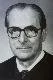 A black-and-white photo of a man wearing glasses and a suit