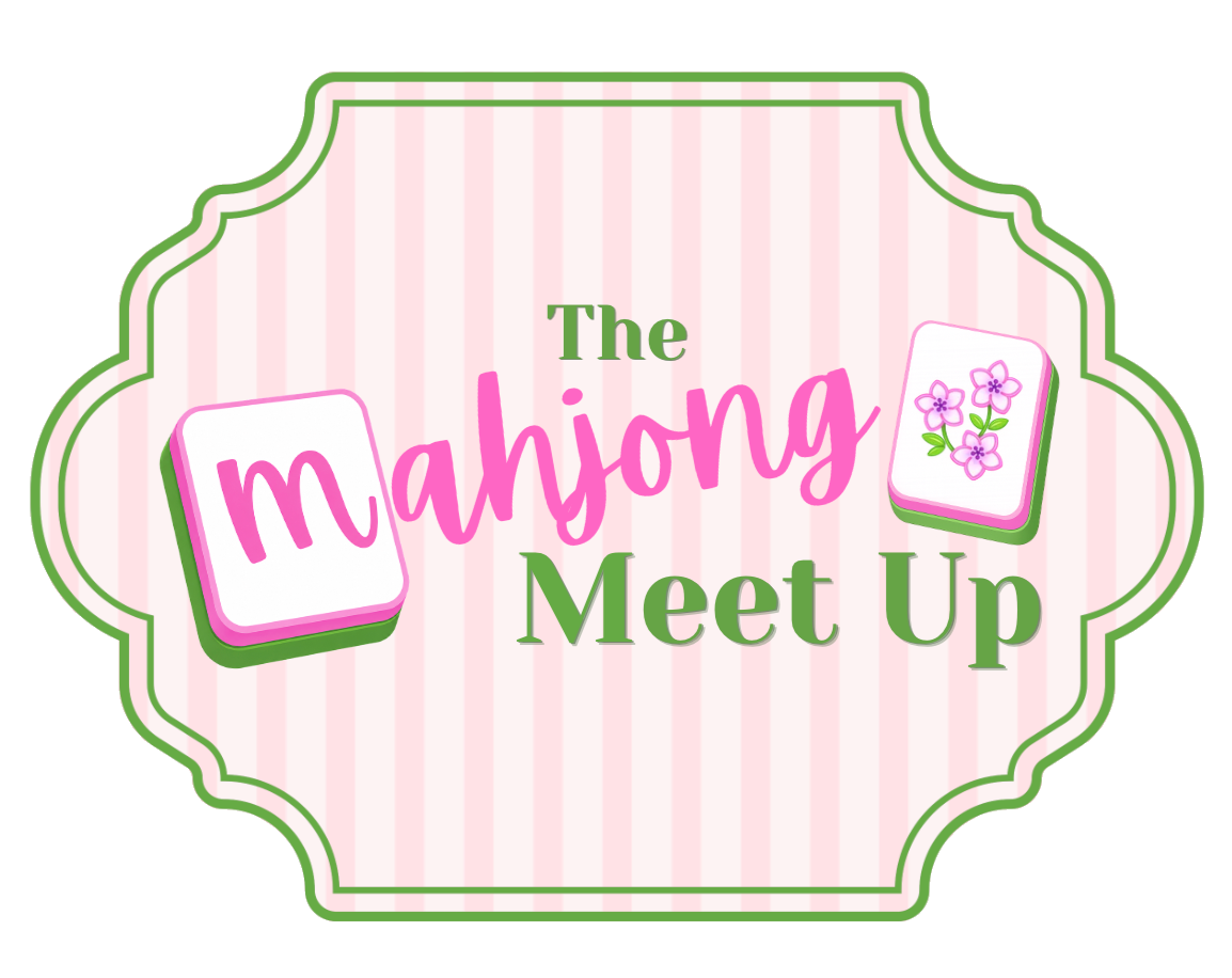 A decorative sign with pink and green colors advertising a Mahjong meet-up event, labeled 'The Mahjong Meet Up' with floral and Mahjong tile graphics.