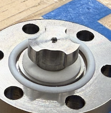 Close-up of a metallic valve with a white handle on a wooden surface.