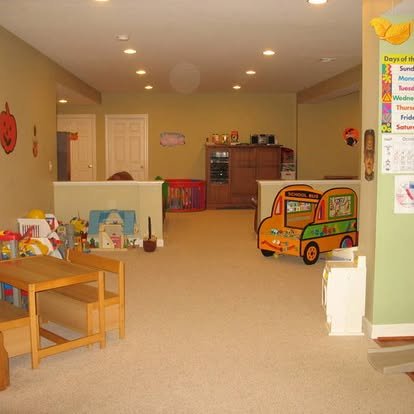 A children's playroom with toys, educational materials and a colorful toy bus on the floor.