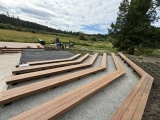 This project combines several rows of angled wood seating with open aisles. The arrangement faces the platform area and follows the shape of the surrounding outdoor space.
