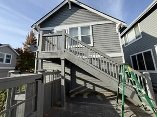 This home is shown before the major exterior renovation began. The project included replacing the original staircase and railings, updating the siding, and adding a coordinated wood fence and gate.
