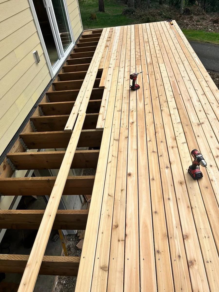 This deck update involves installing new wood boards across the supporting frame. The project is shown underway, with decking in place across much of the surface and remaining sections still open.