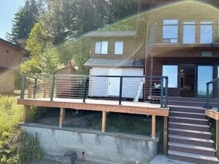 The raised deck project includes a broad platform, perimeter railings and stairs along the side of the home. This view shows how the deck surface and supporting structure fit the property’s changing ground level.