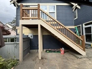 This view highlights the rebuilt staircase, elevated landing and wood railings alongside the updated siding. Together, these elements show how the stair and exterior work fit into the home’s larger renovation.