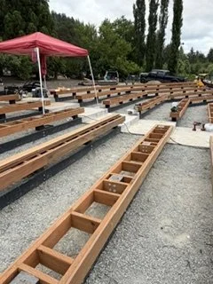 Construction includes assembling long bench frames with regularly spaced blocking. These supports form the base for the seating surfaces throughout the outdoor gathering space.
