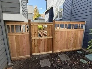 Matching fence panels and a central wood gate complete the side-yard enclosure’s layout. The gate maintains access between the homes, while the surrounding panels provide privacy and complement the exterior updates.