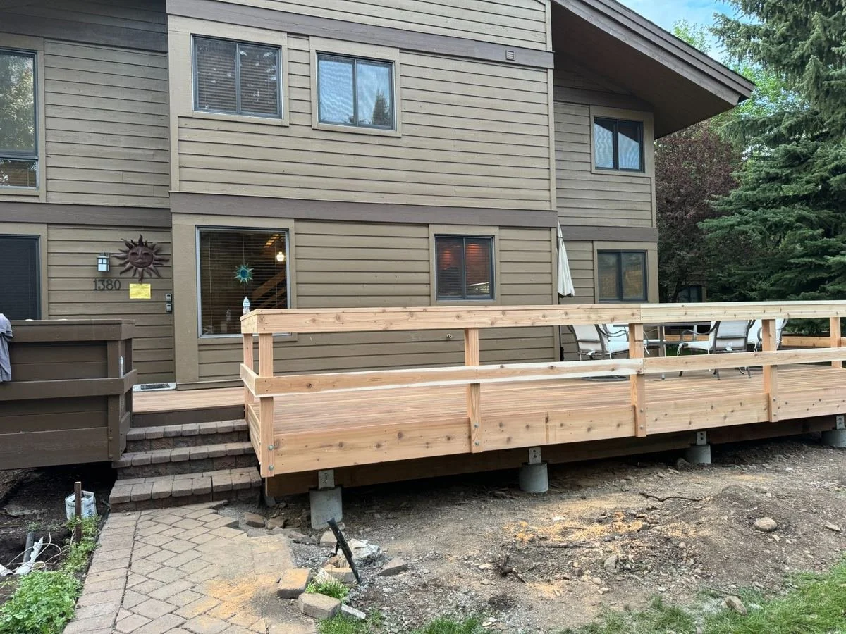 This project updates the outdoor deck with new wood decking and railing components. The layout connects to the existing masonry steps and provides space for outdoor seating alongside the home.