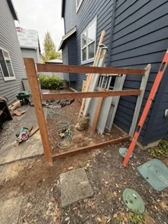 As part of the same exterior renovation, wood posts and horizontal rails establish the new side-yard fence. This framework prepares the enclosure for privacy boards and a decorative upper section.