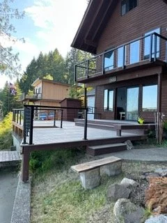This angle highlights the side steps, finished deck edges and black railing system. These elements connect the main deck to the surrounding yard while complementing the home’s exterior.