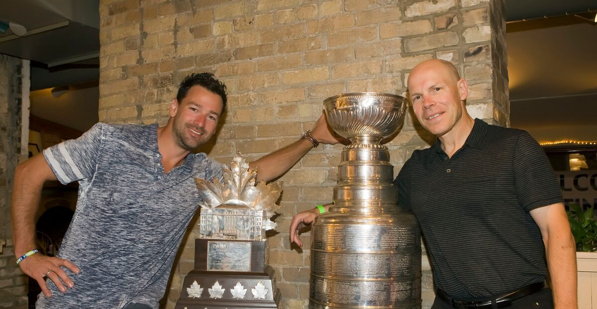 Justin Williams and Thane Campbell from PCIHockey pose with the Conn Smythe Trophy and the Stanley Cup