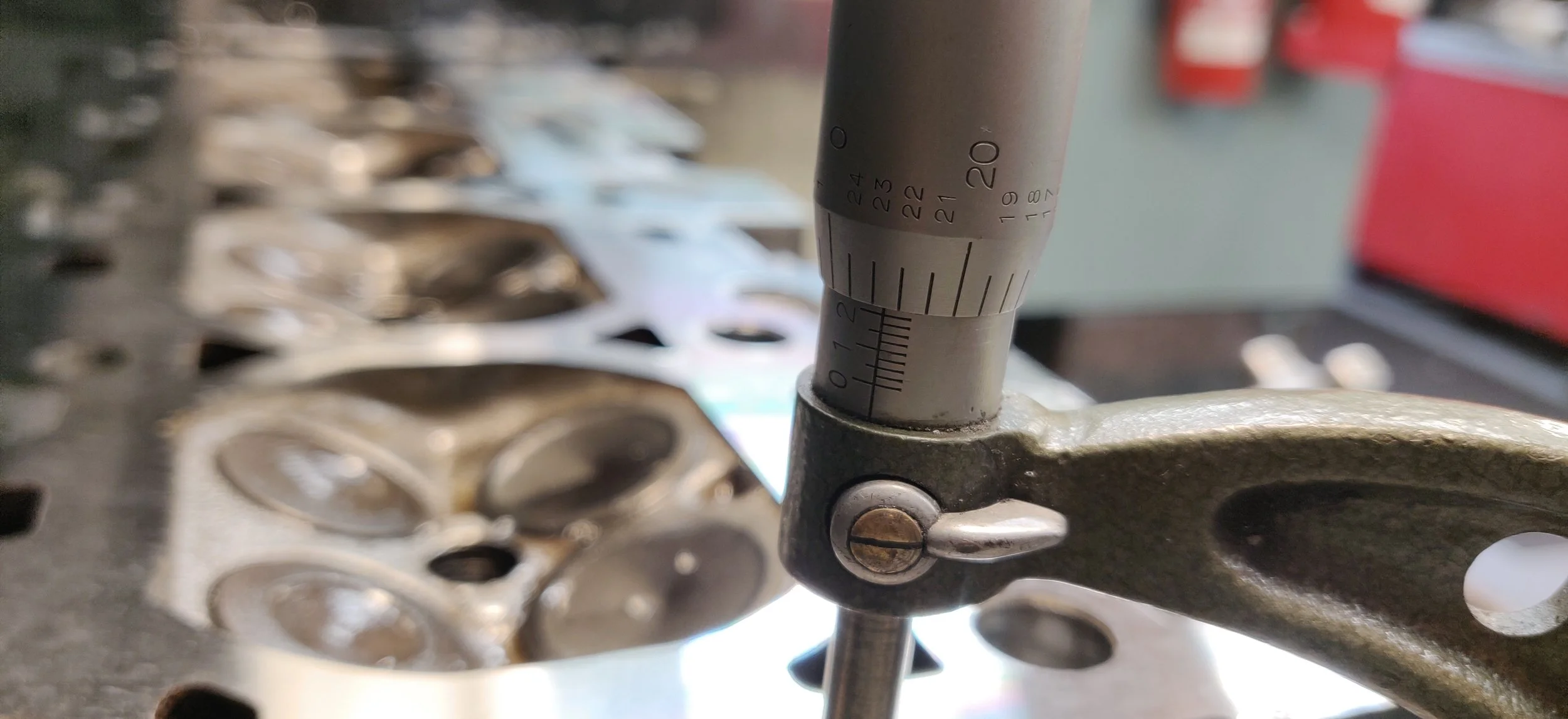 Measuring cylinder head thickness using a micrometer.