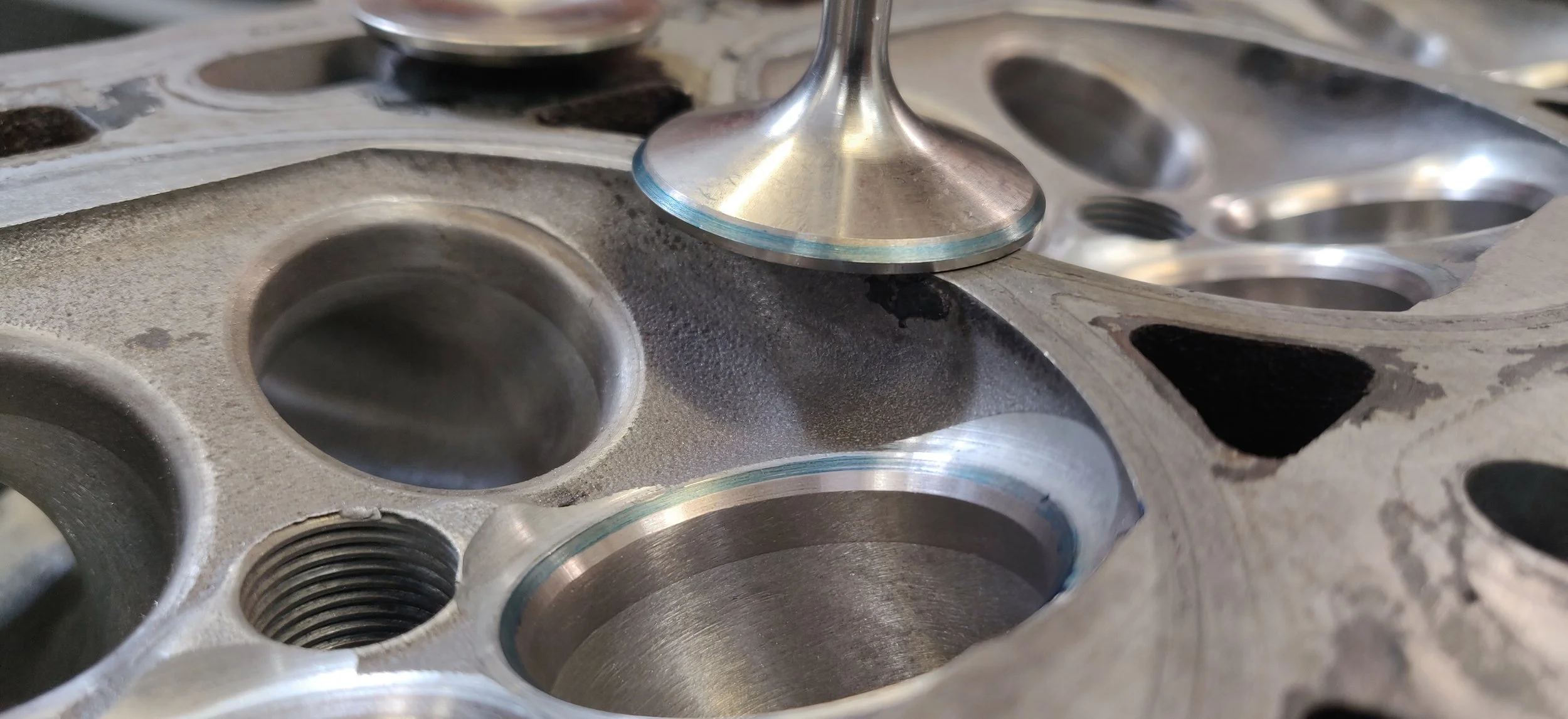 Close-up of a cylinder head with an engine valve resting on its surface.